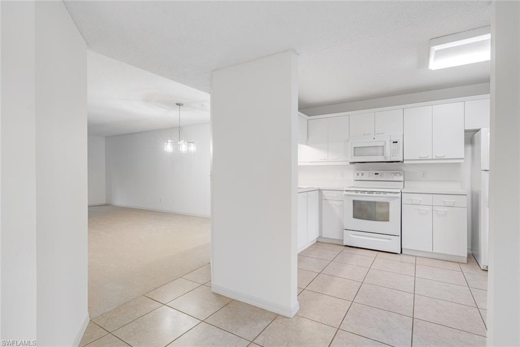 7761 Jewel Lane, Unit 103 Naples, FL 34109 - Photo 4 of 26 a kitchen with white cabinets and white appliances