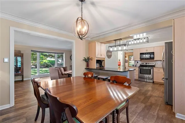a dining room with wooden floor a chandelier a wooden table and chairs