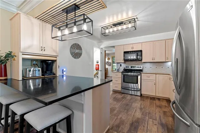 a kitchen with stainless steel appliances granite countertop a sink a stove top oven a chimney and cabinets