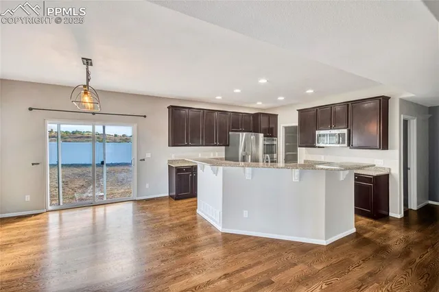 a kitchen with stainless steel appliances granite countertop a refrigerator a stove and a sink with wooden cabinets
