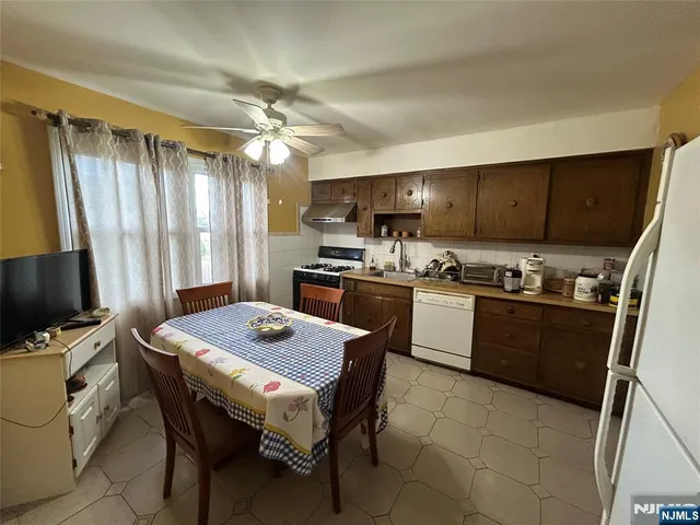 a kitchen with a stove a sink dishwasher a refrigerator with a dining table and chairs