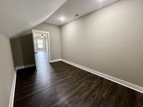 an empty room with wooden floor ceiling fan and windows