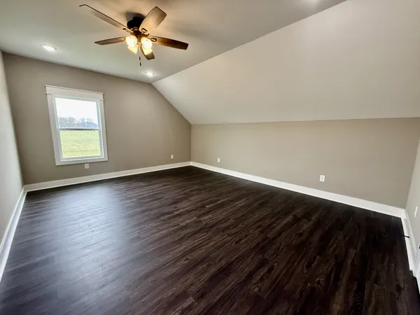 an empty room with wooden floor fan and window