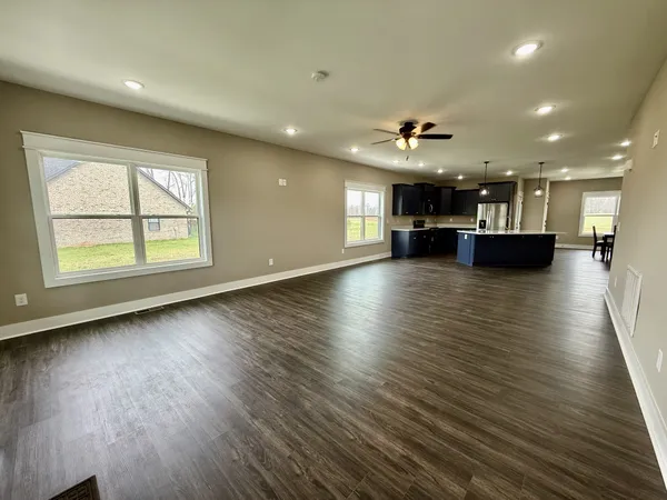 an empty room with wooden floor and a kitchen