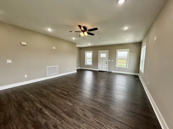 an empty room with wooden floor and windows