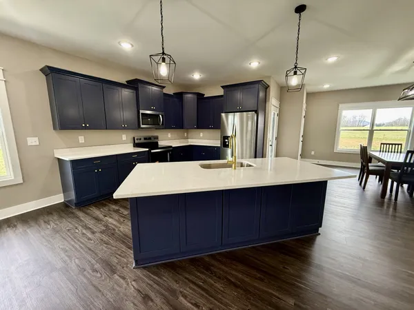 a kitchen with kitchen island granite countertop wooden floors a sink stainless steel appliances and cabinets