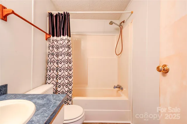 a bathroom with a granite countertop bathtub shower sink vanity and toilet