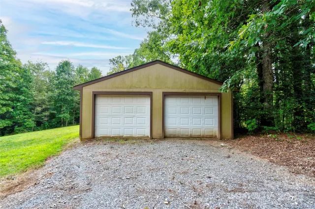 a view of a house with large trees and a small yard