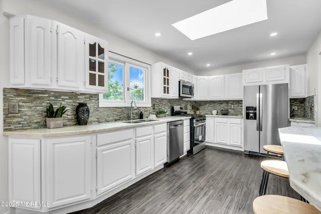 a kitchen with white cabinets stove and white stainless steel appliances