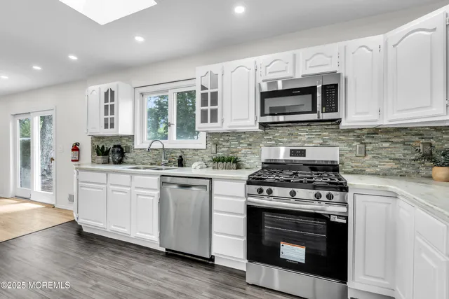 a kitchen with stainless steel appliances granite countertop a stove top oven a sink dishwasher a refrigerator and a microwave