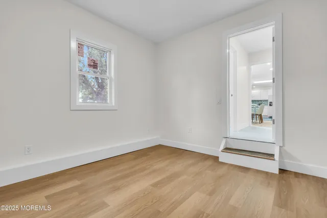 an empty room with wooden floor and window