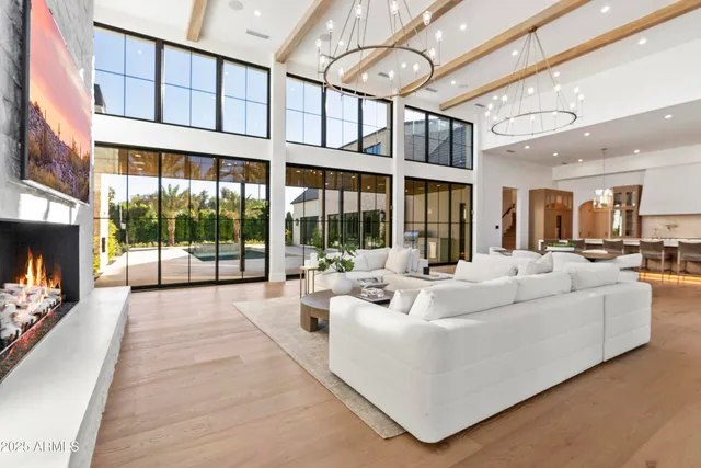 a living room with large windows and a chandelier