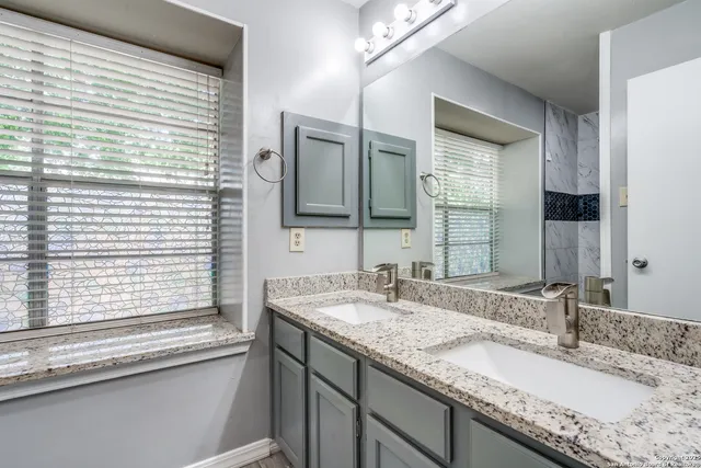 a bathroom with a granite countertop sink and a large mirror