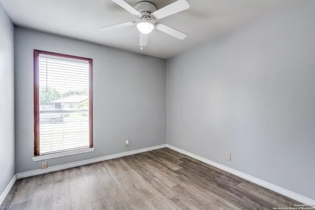 an empty room with a window and a fan