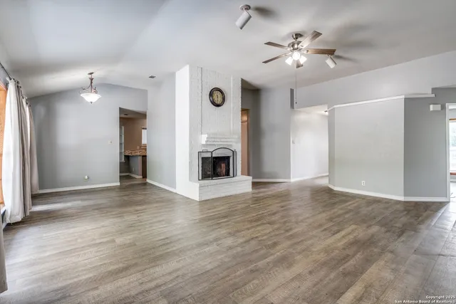 a view of an empty room with a fireplace and a window