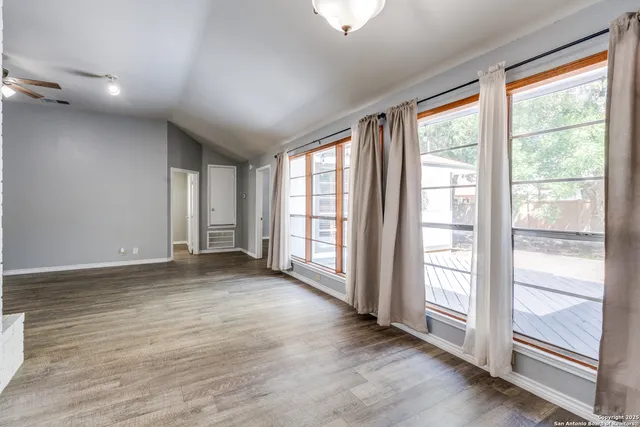 an empty room with wooden floor and windows