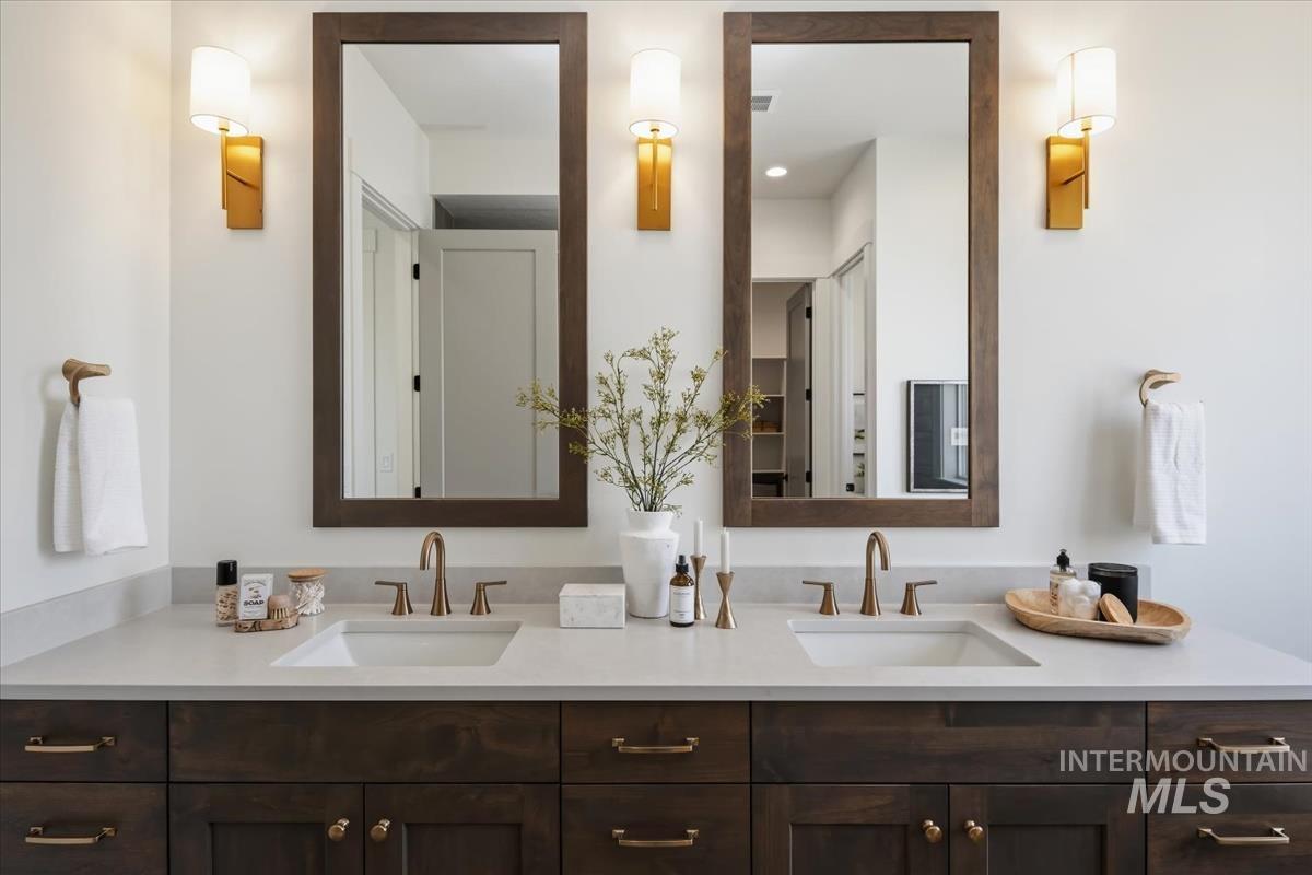 7615 Brown Way Eagle, ID 83714 - Photo 29 of 43 Dual vanity featuring dark wood cabinetry, white integrated sinks, light-toned countertops, and bronze-finish fixtures