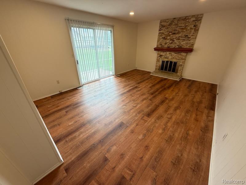 28144 Yorktown Road Farmington, MI 48331 - Photo 6 of 25 Spacious room featuring wood-finish flooring, a stone-clad fireplace with a wood mantle, and sliding glass doors with vertical blinds