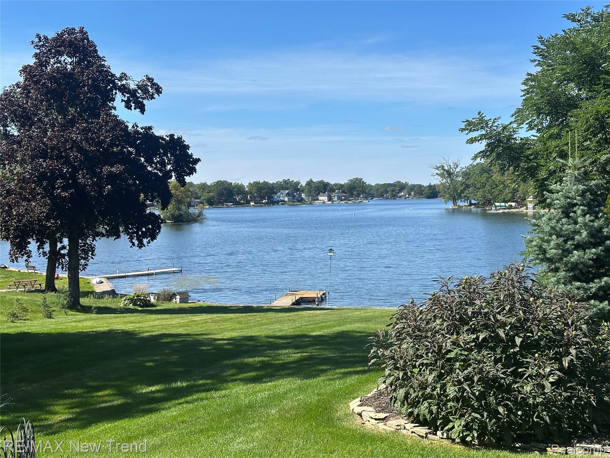 2529 South Commerce Road Walled Lake, MI 48390 - Photo 4 of 66 Expansive waterfront property featuring a manicured lawn, established landscaping, and a private dock on the water