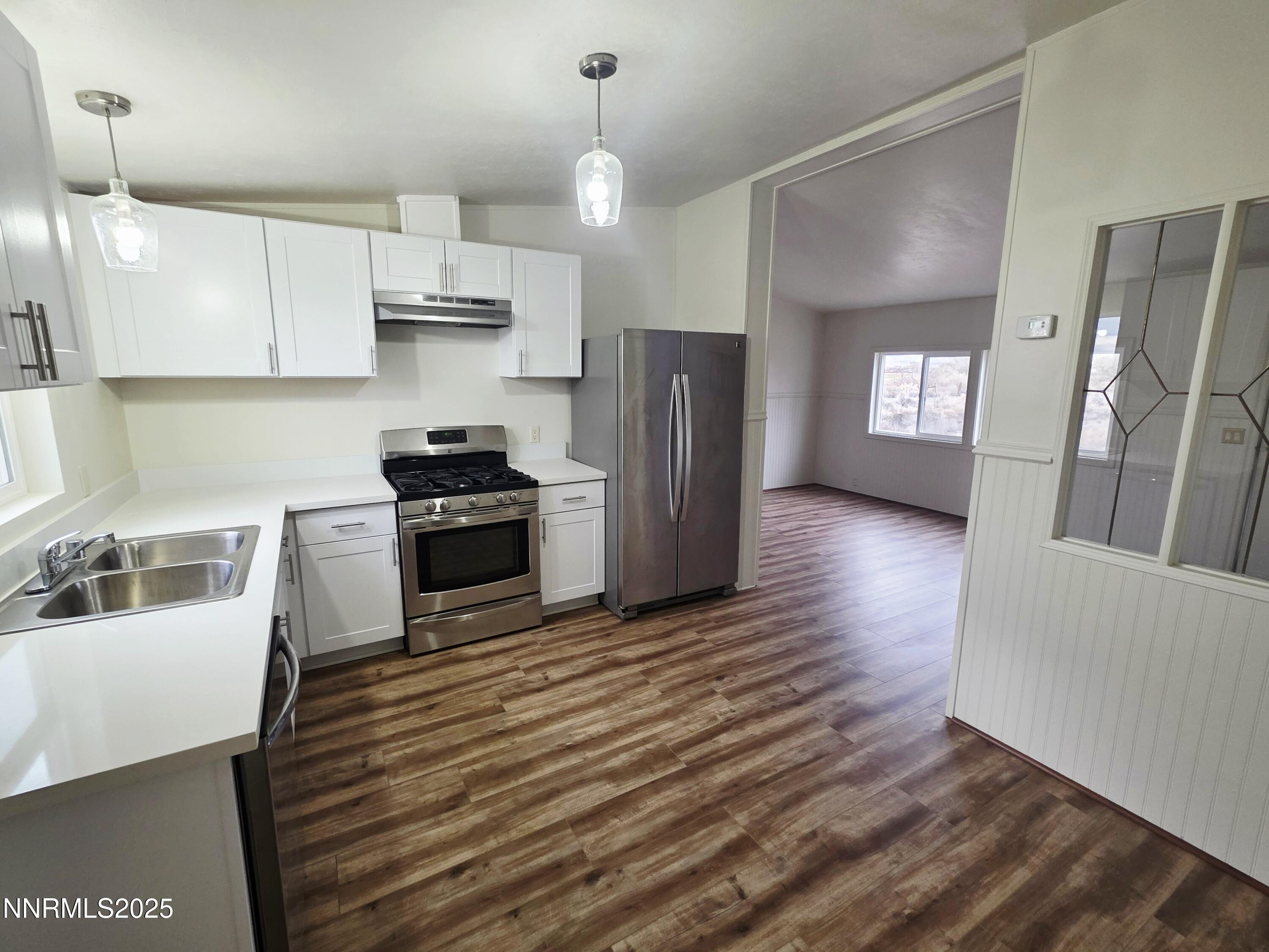 3146 Lone Tree Road Fallon, NV 89406 - Photo 9 of 23 a kitchen with granite countertop a refrigerator a stove a sink dishwasher and white cabinets with wooden floor
