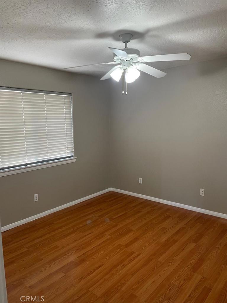 12858 Rain Shadow Road Victorville, CA 92395 - Photo 11 of 15 a view of an empty room with wooden floor and a window