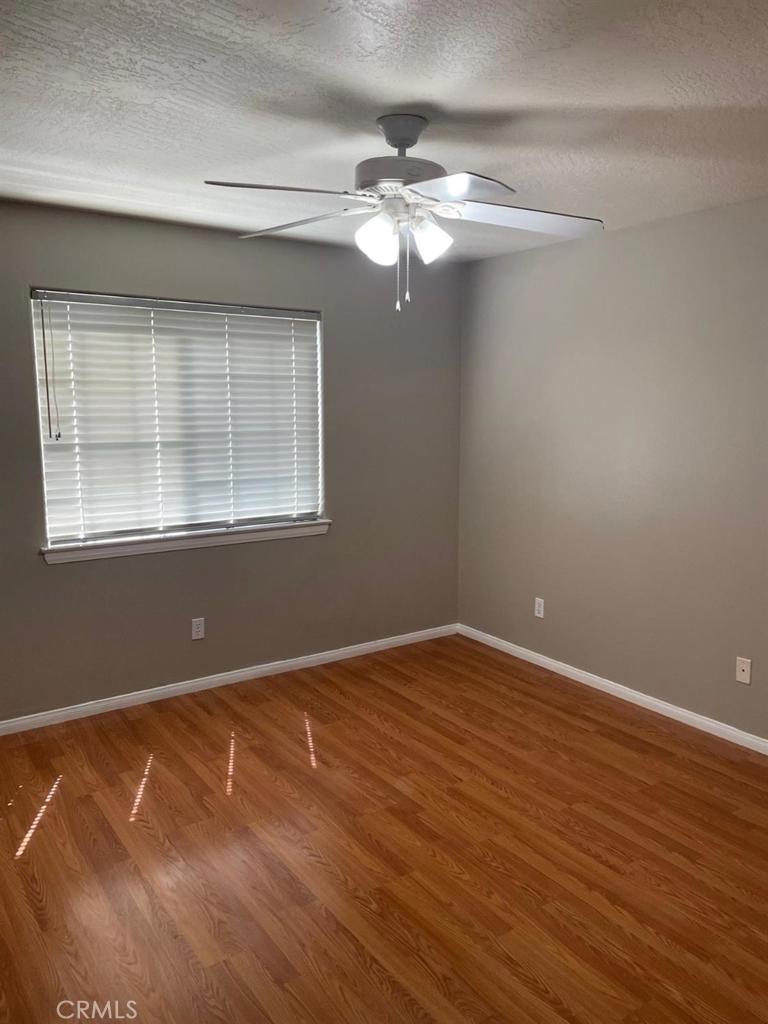 12858 Rain Shadow Road Victorville, CA 92395 - Photo 10 of 15 a view of an empty room with wooden floor and a window