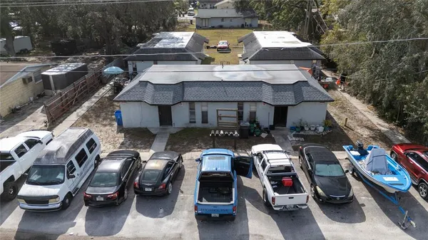 a view of a patio with table and chairs under an umbrella with large trees