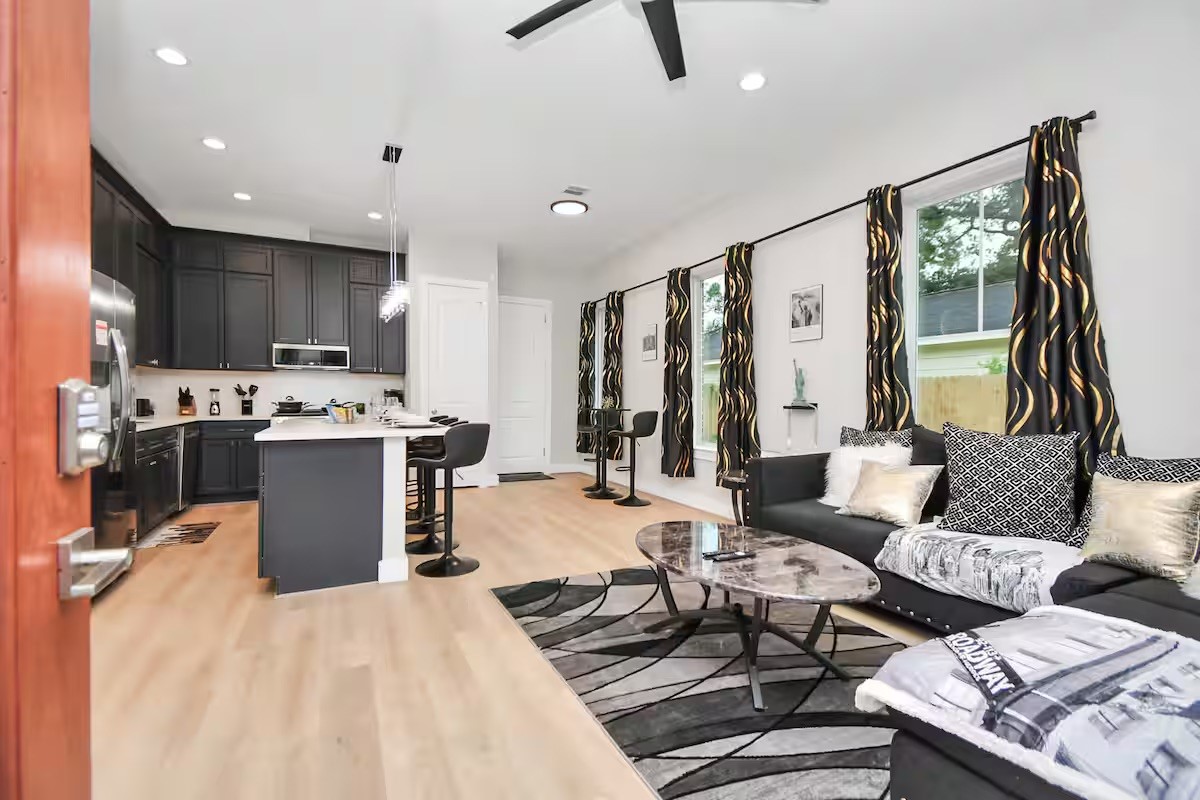 a living room with couches and kitchen view with wooden floor