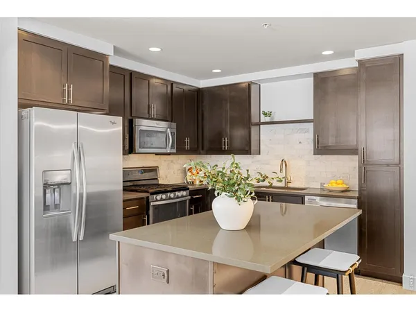 a kitchen with stainless steel appliances granite countertop a sink a stove a refrigerator and a refrigerator