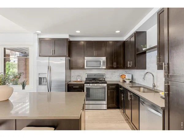 a kitchen with stainless steel appliances a sink a stove a refrigerator cabinets and a dining table