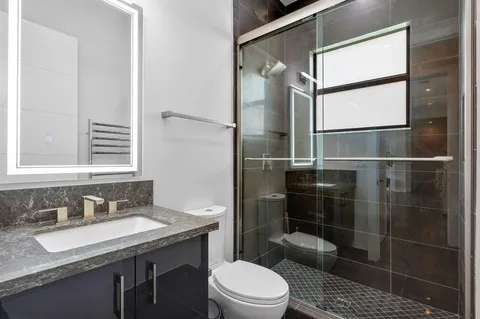 a bathroom with a granite countertop sink toilet a mirror and shower