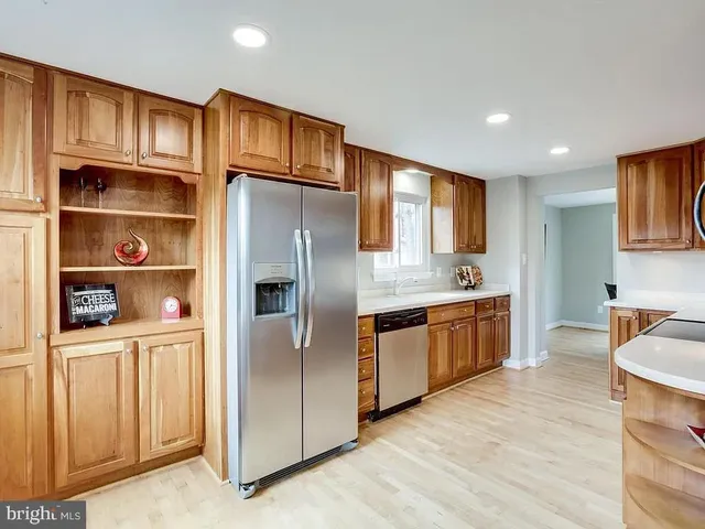 a kitchen with stainless steel appliances granite countertop a refrigerator a sink dishwasher and wooden cabinets with wooden floor