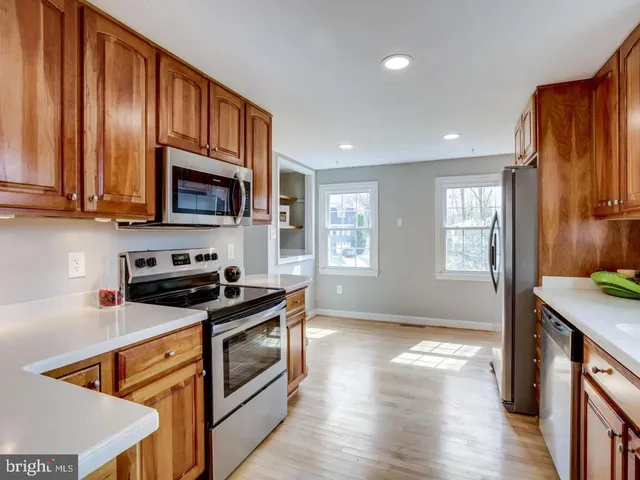 a kitchen with stainless steel appliances granite countertop wooden cabinets a stove a sink and a refrigerator