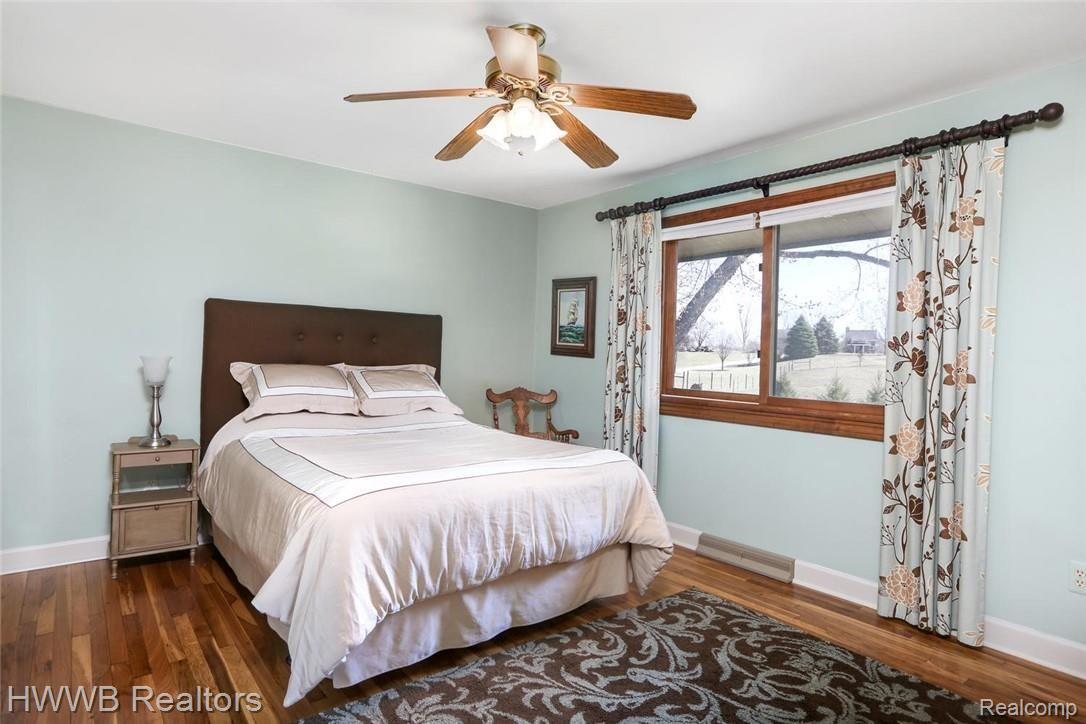 6200 Mack Road Howell, MI 48855 - Photo 26 of 52 This bright bedroom features hardwood floors, ceiling fan, shades and curtains.