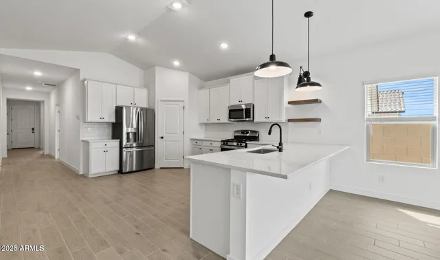 a view of kitchen with stainless steel appliances a stove a sink a refrigerator and cabinets