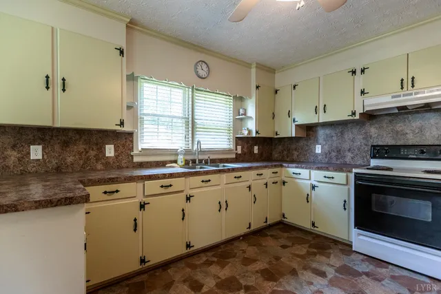 a kitchen with granite countertop white cabinets stainless steel appliances a sink and a window