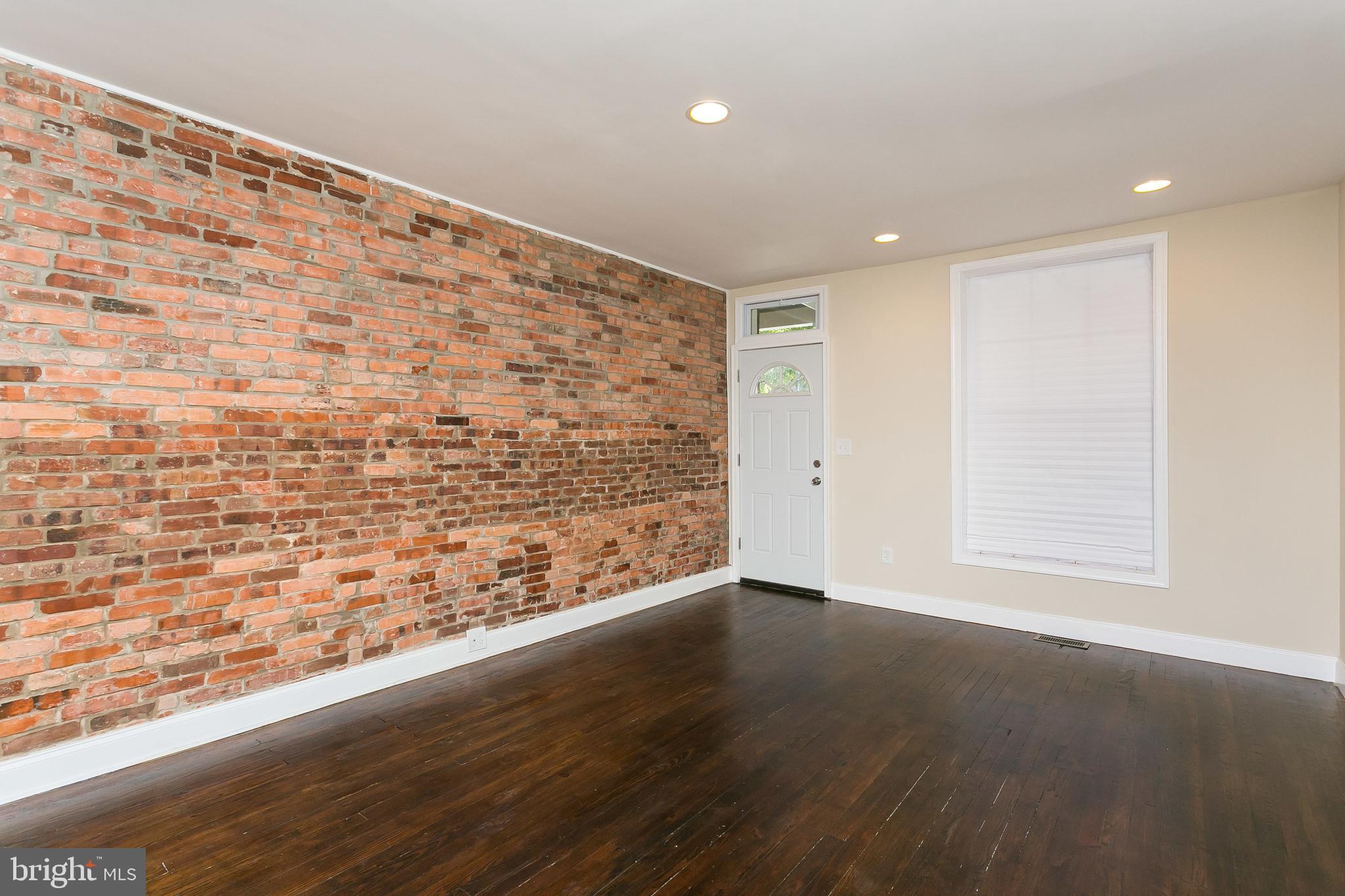 302 East 27th Street Baltimore, MD 21218 - Photo 3 of 31 Large living room with hardwood floors and exposed