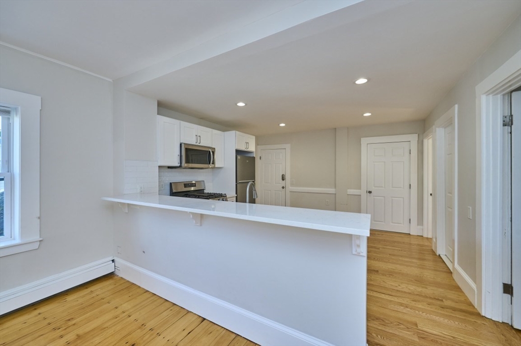 67 Wheatland Street, Unit 2 Somerville, MA 02145 - Photo 8 of 19 a view of a kitchen with wooden floor and a sink
