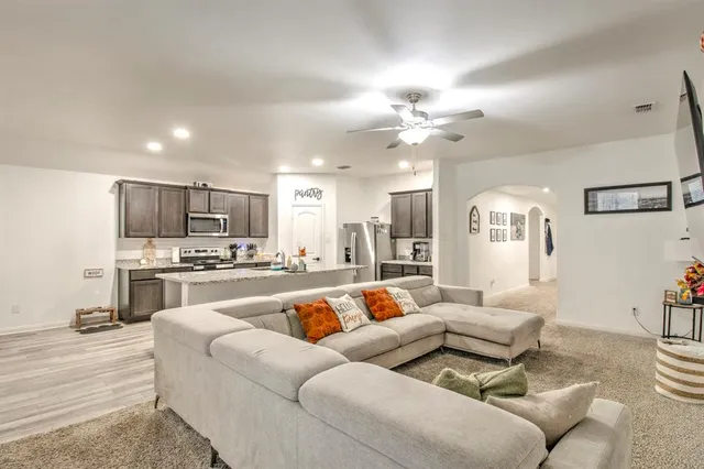 a living room with furniture kitchen view and a chandelier