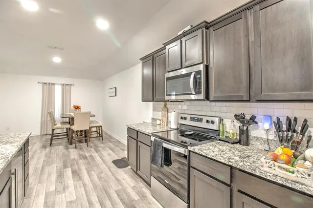 a kitchen with stainless steel appliances granite countertop a stove refrigerator sink and cabinets
