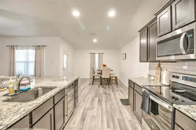 a kitchen with stainless steel appliances granite countertop a stove a sink and a microwave