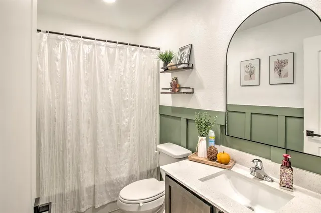 a bathroom with a granite countertop sink a toilet and shower curtain