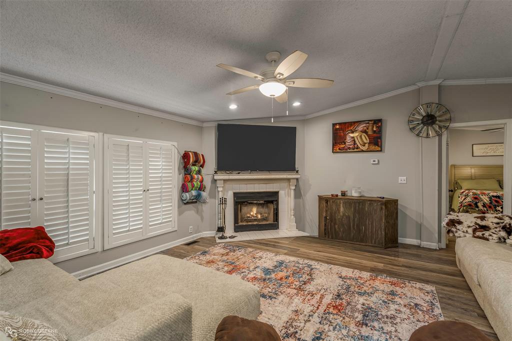 8273 Godfrey Road Shreveport, LA 71129 - Photo 6 of 27 Living area featuring a corner fireplace with a mantel, wood-finish flooring, white plantation shutters, a ceiling fan with integrated lighting, and recessed lighting