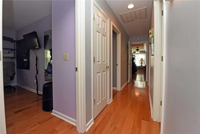 a view of a hallway with wooden floor and a bathroom