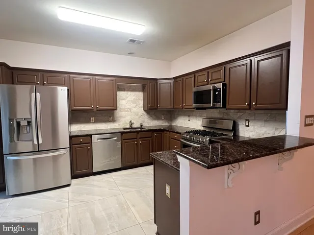 a kitchen with granite countertop a refrigerator stove and microwave