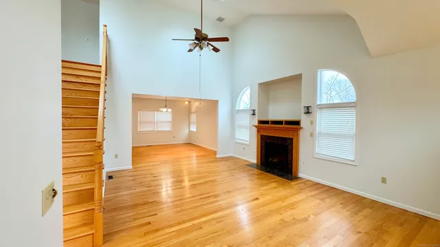 a view of a room with wooden floor ceiling fan and windows