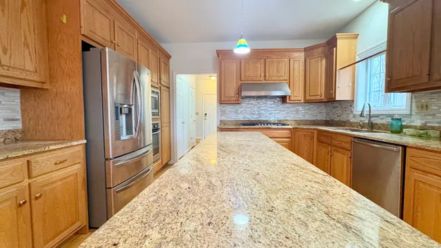 a large kitchen with kitchen island granite countertop a large window cabinets and stainless steel appliances