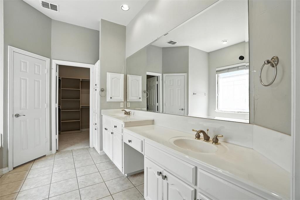 8220 Holliday Road Lantana, TX 76226 - Photo 21 of 40 Spacious bathroom featuring dual vanities with integrated sinks, white cabinetry, a large wall-mounted mirror, and tile flooring