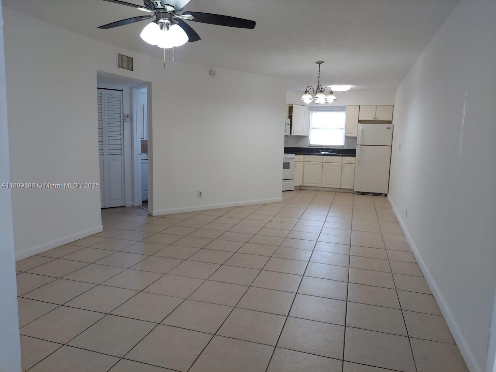 978 Southwest 10th Drive, Unit 9 Pompano Beach, FL 33060 - Photo 4 of 13 an empty room with kitchen and chandelier fan