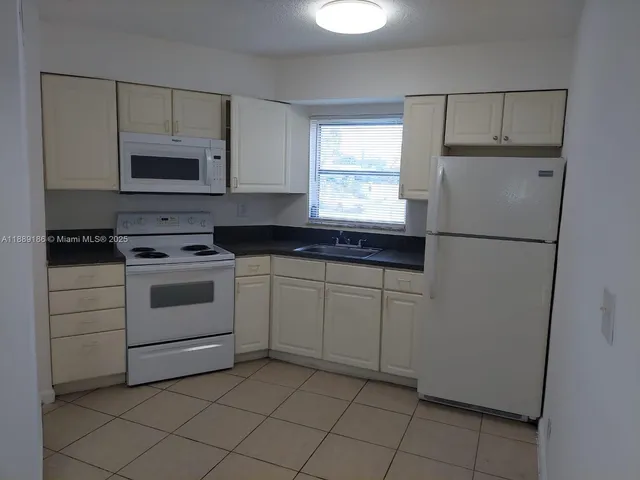 a kitchen with white cabinets and white appliances